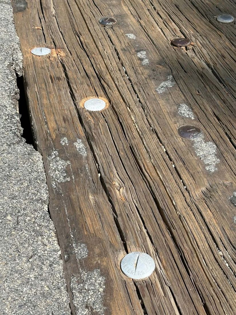 Close view of the bridge’s weathered wooden decking with replaced metal fasteners.